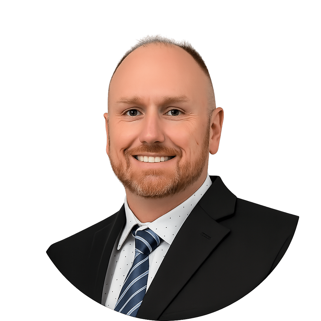 John Judge with short light hair and a beard, wearing a dark suit, white dress shirt with small dots, and a striped tie, posed against a plain white background.